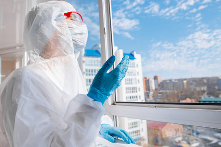 Woman in biohazard medical mask on self isolation quarantine breathes fresh air on balcony with open...