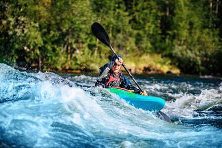 Extreme sport rafting whitewater kayaking. Guy in kayak sails mountain riverの写真素材