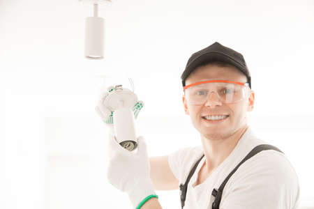 Electrician worker man assembling electric lamps in new apartmentの写真素材