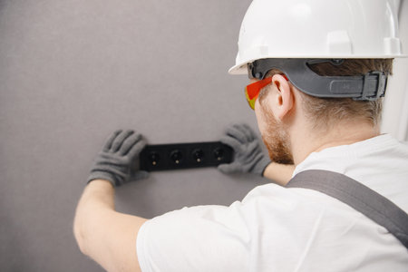 Electrician builder working switches and sockets of residential electrical system, black color