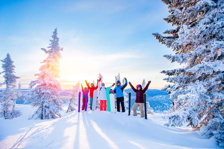 Group of snowboarders and skier dawn with snowboards rejoice snow Light sun in winter forest sunrise. Concept life style, travelの写真素材