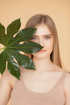 Portrait woman with natural green leaf, blond model girl with clear skin face. Concept Fashion flora beautyの写真素材