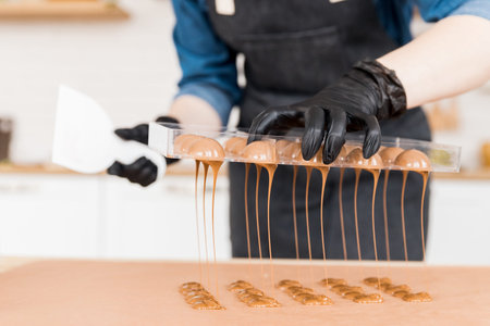Chef or chocolatier making sweet chocolates home on background of kitchen