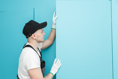 Working male fitter installs hidden invisible installation doors for painting