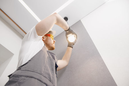 Electrician worker man assembling electric lamps in new apartment.