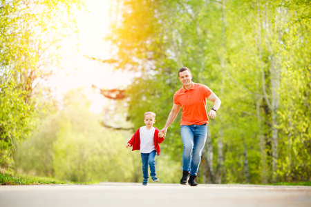Happy family sport concept. Father and son run together on road in summer parkの写真素材