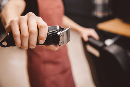 Barber holds hair clipper in modern barbershop for men, brown retroの写真素材