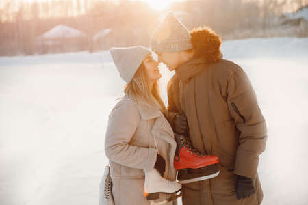 Christmas holidays, young man and beautiful girl hold skates for ice rink in winter, lover coupleの写真素材