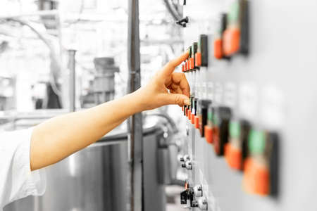 Worker controls automatic machines and production, finger presses industrial buttonの写真素材