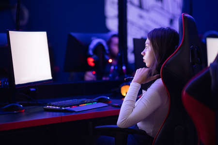 Streamer beautiful girl professional gamer smile playing online games computer with headphones, neon colorの写真素材