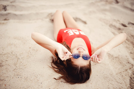 Young woman in red swimsuit relaxing beach. Concept summer holiday, top view