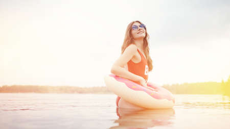 Young woman in red swimsuit inflatable circle donut on beachの写真素材