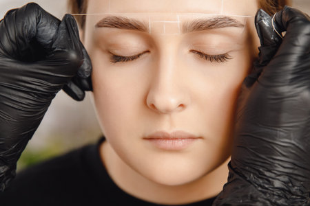 Correction and tinting eyebrows, master applies thread to woman on brow