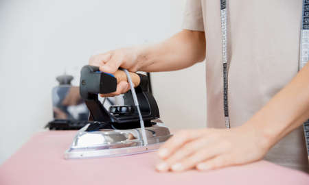 Woman tailor steaming cloth with electric steamer for sewing dressesの写真素材
