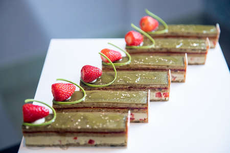 Close-up of pistachio chocolate dessert with strawberries and nuts, catering table settingの写真素材