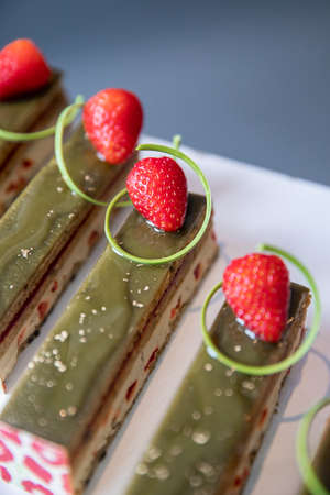 Close-up of pistachio chocolate dessert with strawberries and nuts, catering table settingの写真素材