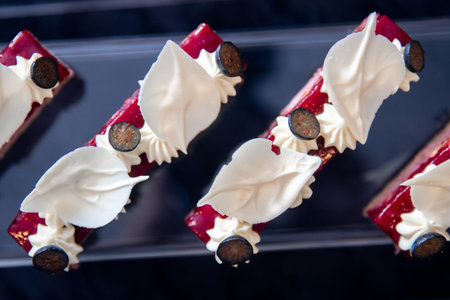 Catering table with sliced chocolate cakes decorated with fresh raspberries and nuts