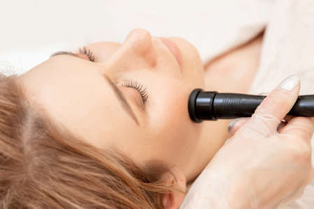 Young woman receiving RF lifting electric facial massage for face skinの写真素材