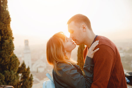 Romantic couple man and girl hug and kiss on sunset background of city Verona Italy. Travel conceptの写真素材
