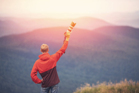 Traveler blogger takes photos with camera on top of mountain, sunset photo from back