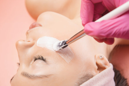 Close-up young woman applying cream for skin care with brush. Spa beauty treatment concept