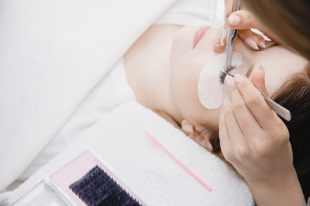 Eyelash extension procedure woman, tweezers fake long lashes beautiful female eyes