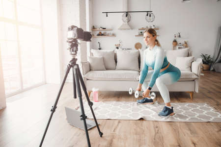 Fitness influencer woman recording video training home on camera. Concept Lifestyle blogger sport and recreationの写真素材