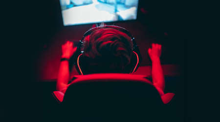 Professional gamer playing online games tournaments pc computer with headphones, Blurred red and blue backgroundの写真素材