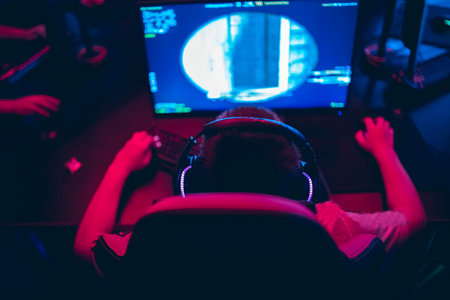 Professional gamer playing online games tournaments pc computer with headphones, Blurred red and...