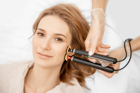 Young woman receiving RF lifting electric facial massage for face skin