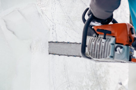 Ice sculpture carving man use chainsaw cut frozen winter