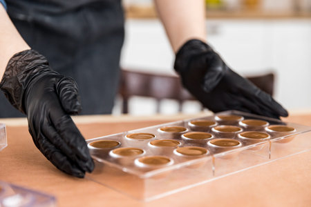 Confectioner woman in apron shows molds for making sweet chocolates. Startup home business concept