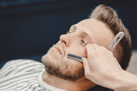 Barber process shaving razor bearded hipster man in barbershopの写真素材