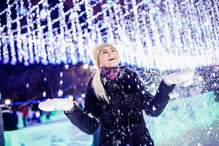Portrait young beautiful girl rejoices to first snow and winter,, evening illumination backgroundの写真素材