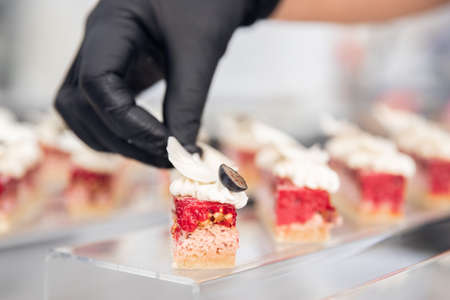 Chef hand in patisserie restaurant prepares cakes and decorates with chocolate icingの写真素材
