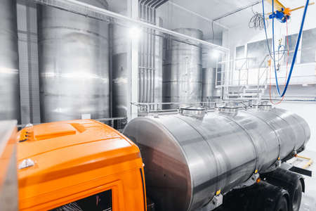 Dairy factory industry, milk tanker truck pumps products into steel storage tanksの写真素材