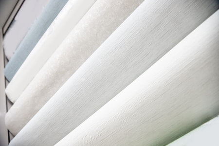 Samples of different colorful rolls of wallpaper in shop, choice in row market