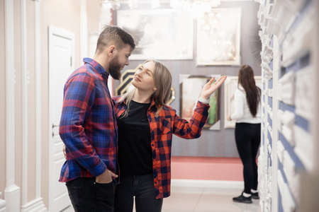 Young couple selects materials for renovation of new apartment in storeの写真素材