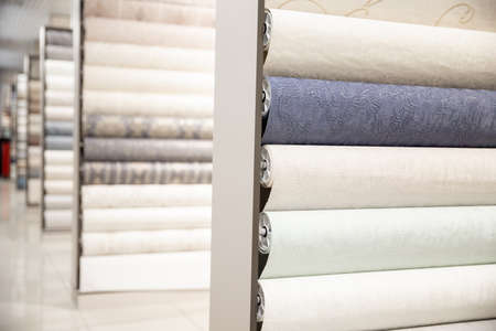Samples of different colorful rolls of wallpaper in shop, choice in row marketの写真素材