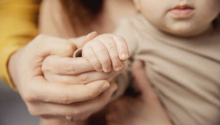 Close-up photo of family hands, baby son holding mom and dad fingerの写真素材