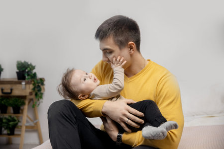 Small baby touches father man face with hand, light background home