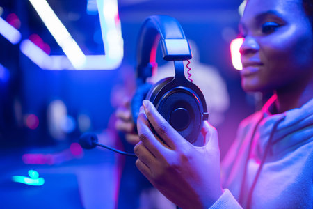 Headphones with microphone in hands of african happy woman webcam online video gameの写真素材