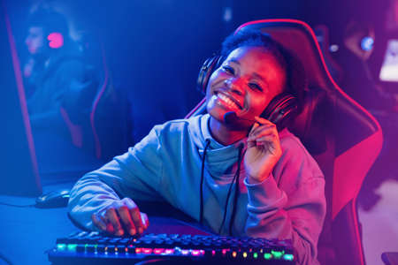 Young african happy woman professional gamer win in online video game with headphones, neon backgroundの写真素材