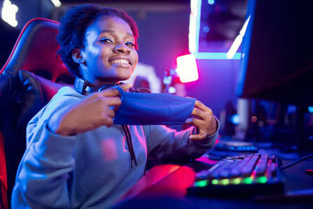 Streamer African American gamer beautiful woman holds protective mask against virusの写真素材