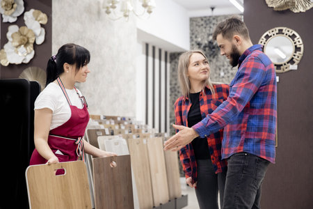 Laminate on market, couple man and girl worker chooses parquet flooring in house, consultant talks about advantages of materialの写真素材