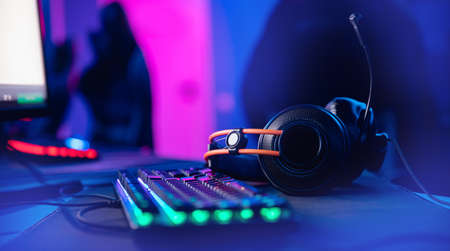 Professional headphones with microphone for video games and cyber sports gaming monitor in neon color blur backgroundの写真素材