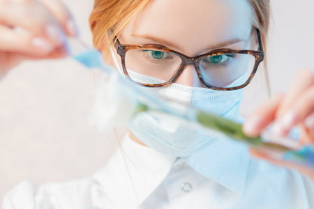 Scientist extracts oil syringe from flowers test natural cosmetics extract aroma. Buds leaf in glass flask. Biotechnology conceptの写真素材