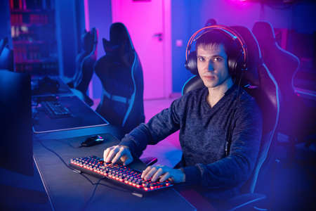 Streamer young man rejoices in victory professional gamer playing online games computer with headphones, neon colorの写真素材