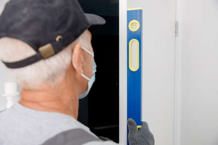 Worker in medical mask use silicone tube gun for repairing and installing window. Concept service technicianの写真素材