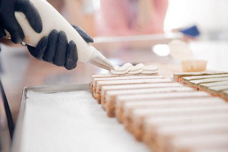 Pastry chef applies buttercream to cakes in restaurant kitchen